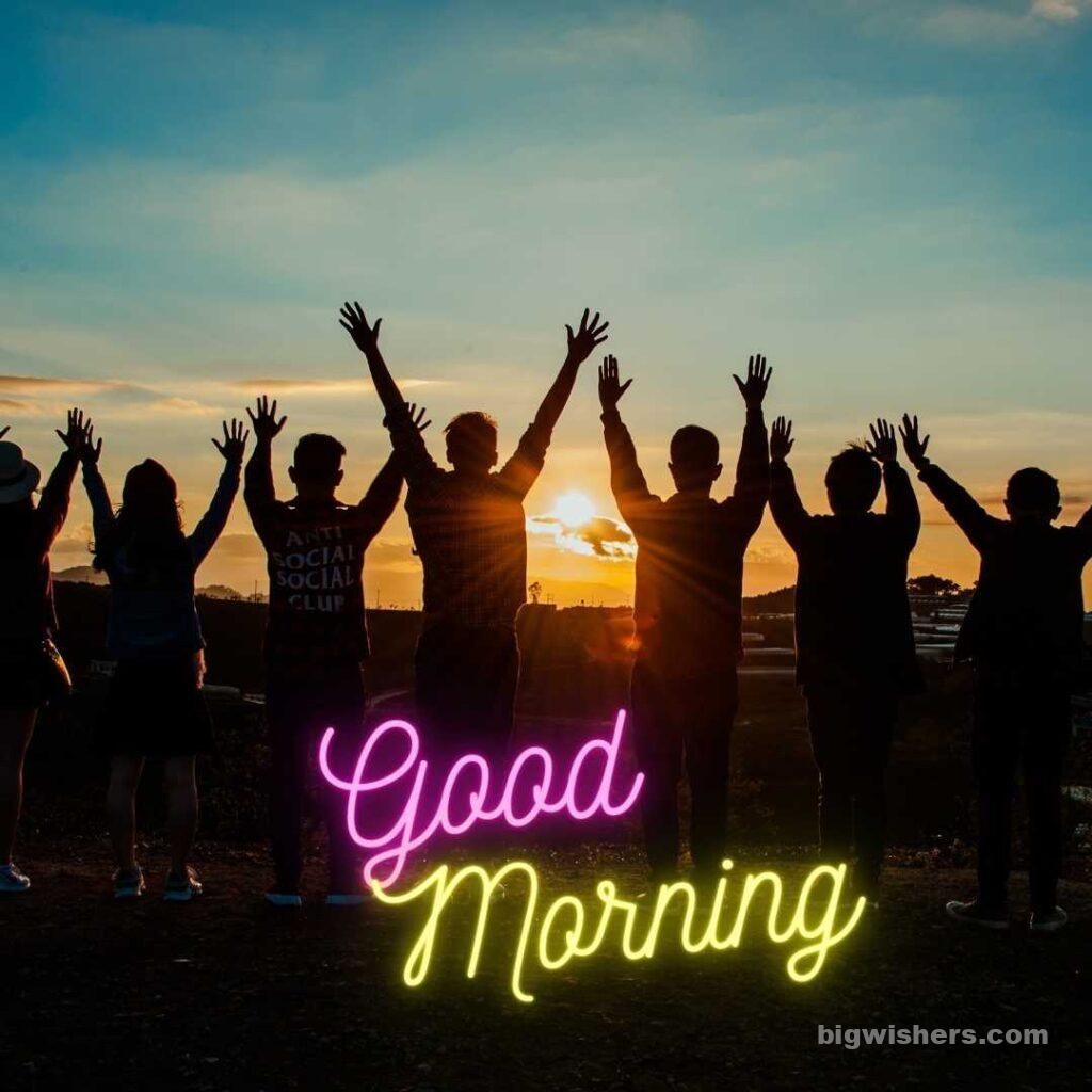 Friends are stood with hands up in early morning written Good Morning
