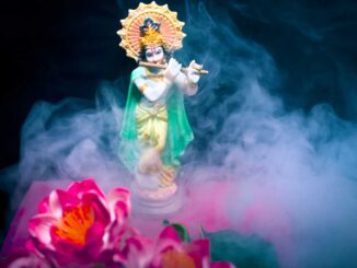 a statue of lord krishna with flowers in the background.