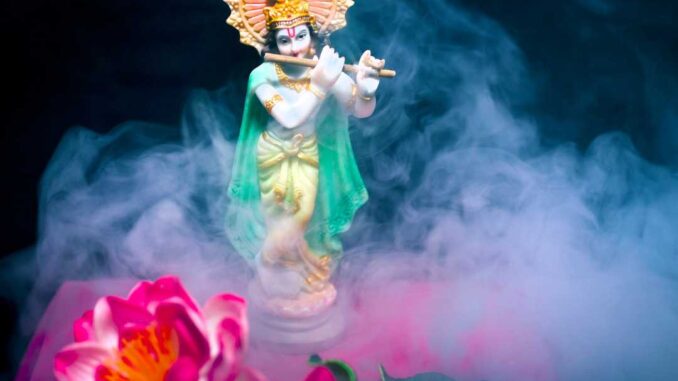 a statue of lord krishna with flowers in the background.
